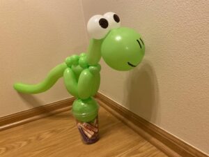 A dinosaur on a cup with candy in it